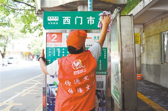 志愿者在认真擦拭公交站牌，希望它每天都以一尘不染的容貌迎接市民。特约摄影师